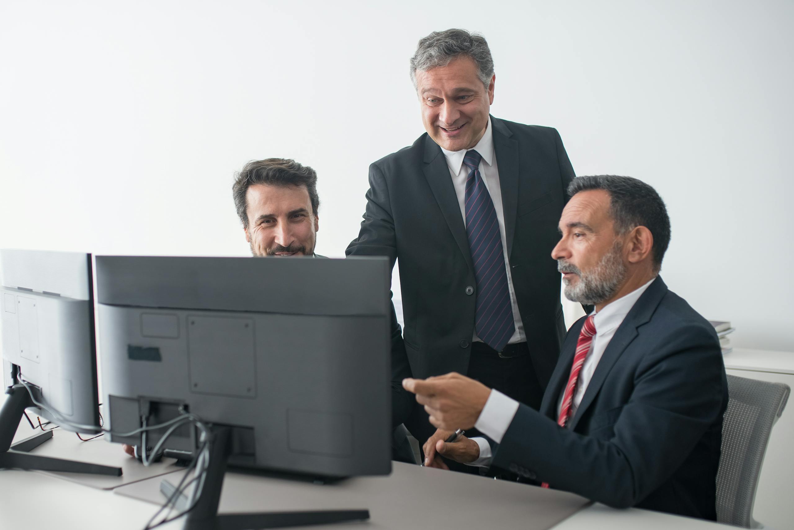 Three business colleagues in suits happily collaborating at the office.